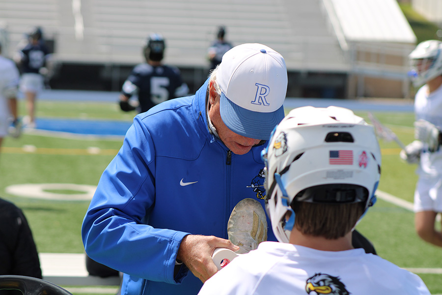 Rockhurst athletic trainer Paul McGannon works to re-tape the ankle of senior Henry Kemp during a lacrosse match versus SLUH on April 30, 2023. McGannon, a Rockhurst grad, joined the staff in 2010.