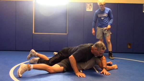 Wrestling coach Rich Wikiera teaches a couple of his athletes technique during preseason workouts.