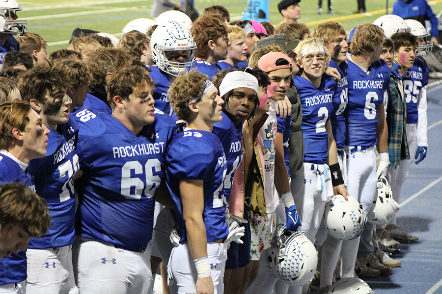 The football team stands with the yell leaders in front of the student section to sing the Rockhurst alma mater following their 40-22 win over SLUH on Oct. 13, 2023.