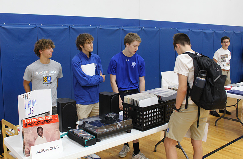 Juniors Brady Goffinet, Charlie Porto and ?? work the Album Club table as a student looks through some of the albums during the Freshman Club Fair on Sept. 21, 2023.
