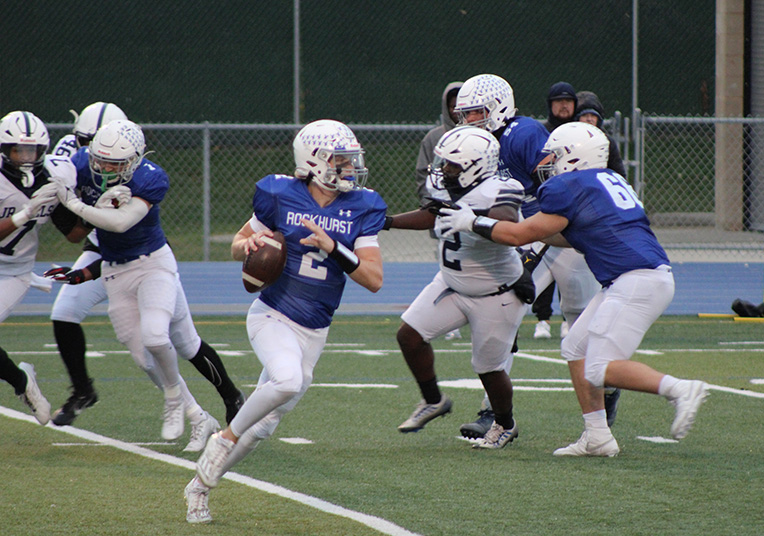 Senior quarterback Ethan Hansen rolls to his right looking for a receiver during the varsity game against SLUH on Oct. 13, 2023. Hansen would throw for 242 yards and three touchdowns on Senior Night in leading the Hawklets to a 40-22 win. I trust my teammates to make plays when I give or pass them the ball and people wanted to make plays...so props to my teammates.