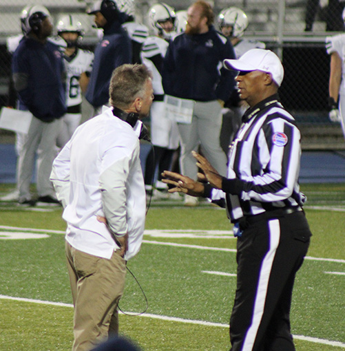 Head coach Kelly Donohoe talks with the referee after a penalty was called on a Rockhurst player. The game versus SLUH on Oct. 13, 2023 was already decided by this point, but the Junior Billikens would go on to score a final touchdown on this drive to make the final score 40-22.