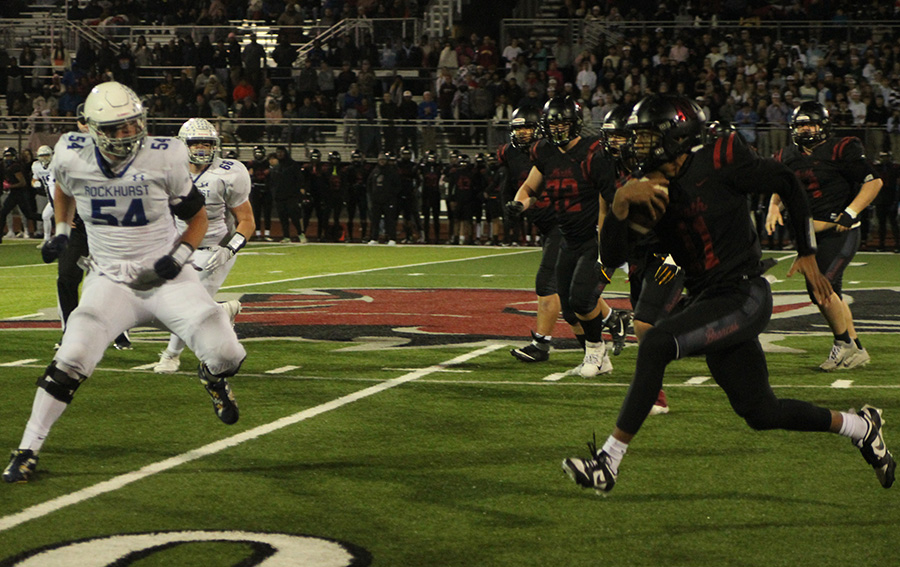 Rockhurst senior defensive lineman Andrew Sprague (54) looks to cut off Lees Summit North quarterback Elijah Leonard late in the district championship game on Nov. 10, 2023. Sprague and his Hawklets teammates got the best of the matchup, winning 24-21.