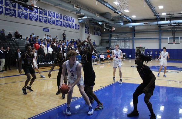 Sophomore Kevin Sullivan evaluates his options as the Ruskin defense collapses on him during the first game of the season on Nov. 28, 2023. Sullivan would lead the Hawklets in scoring with 22 points in his first varsity start. Rockhurst would win going away 73-49.