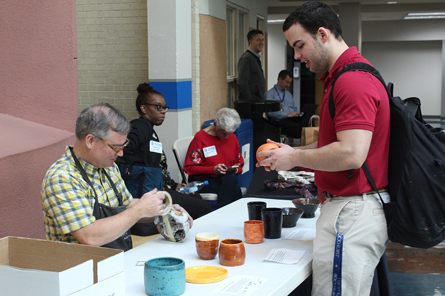 Senior Graham Schaaf (right) examines a piece of pottery made by Tate Owens (left) students during the Fair Trade Fair on Dec. 7, 2023. The money made from the sale of the student work went to help support a pair of students in Kenya and the Philippines through the organization Unbound.