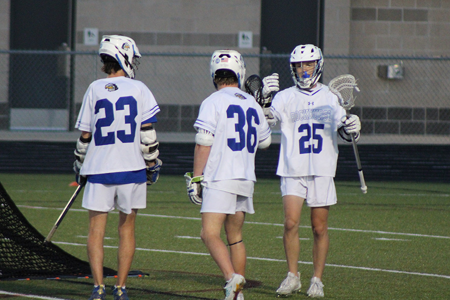 Senior Reid Moshier (25) congratulates sophomore Gentry Curtis (36) after Curtis scored a goal to put Rockhurst up 19-5 on Olathe during the LAKC semifinals on May 22, 2024. Also pictured, senior Teddy Brewster (23).