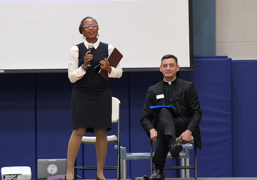 Danielle Brown from the USCCB talks to the Rockhurst student body Men for Others Day on Sept. 9, 2024 as principal Father Vincent Giacabazi looks on. Brown addressed the topics of dignity, justice and belonging on this day intended to help the students understand what it looks like to be a 'man for others'.