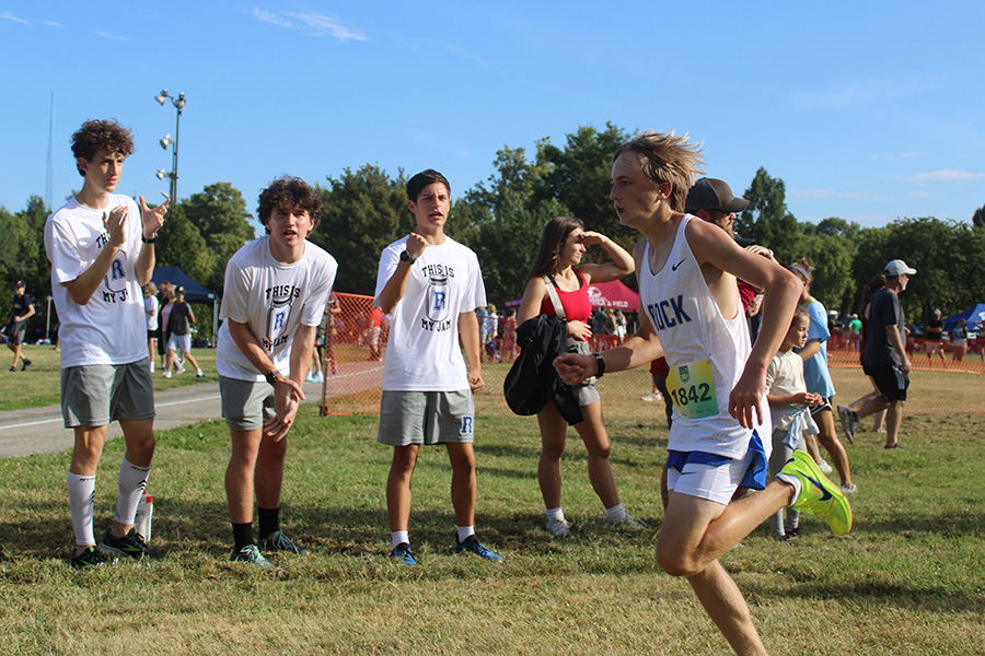 Freshman Jack McGovern pushes towards the finish line while teammates urge him on during the varsity race of the Forest Park XC Festival 2024 on Sept. 14, 2024. McGovern would finish 13th.