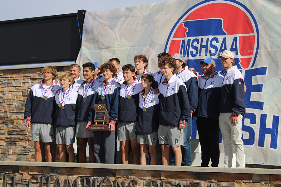 The Rockhurst cross country team and coaches pose for a picture with their  trophy after winning the Missouri Class 6 cross country championship on Nov. 8, 2024.