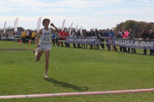 Senior Henry Acorn raises his hands in victory as he nears the finish line of the Missouri Class 6 cross country championship on Nov. 8, 2024. Acorn finished first, more than eight seconds ahead of the nearest competitor.