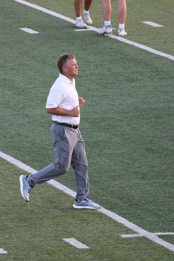Head coach Kelly Donohoe jogs across the field as his team warms up for their game against Blue Springs on Oct. 3, 2025.