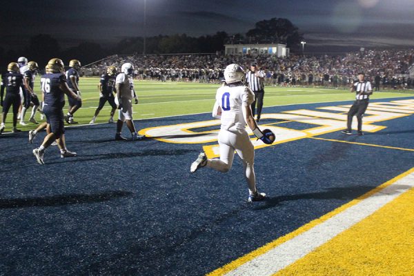 Junior running back Cash Lewandowski heads toward the officials to give them the ball after scoring the Hawklets' first touchdown of the game against St. Thomas Aquinas on Oct. 10, 2025. It was the first of Lewandowski's three TDs on the day, the last of which led to the game-winning 2-point conversion in overtime.