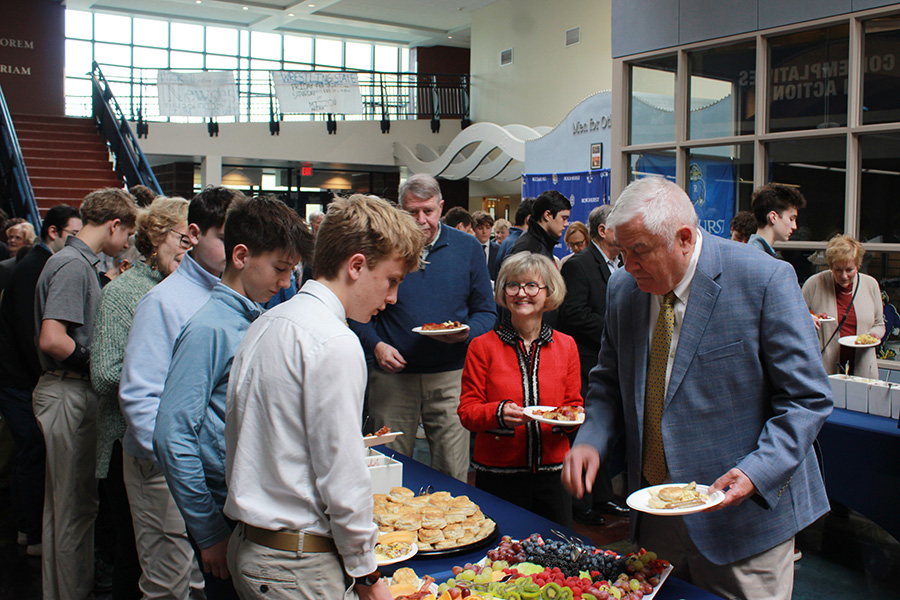 Freshman Sam Schwaller (in blue) and sophomore Jack McGovern (white shirt) load up their plates during the brunch portion of the Grandparents Mass and Brunch on March 1, 2026.