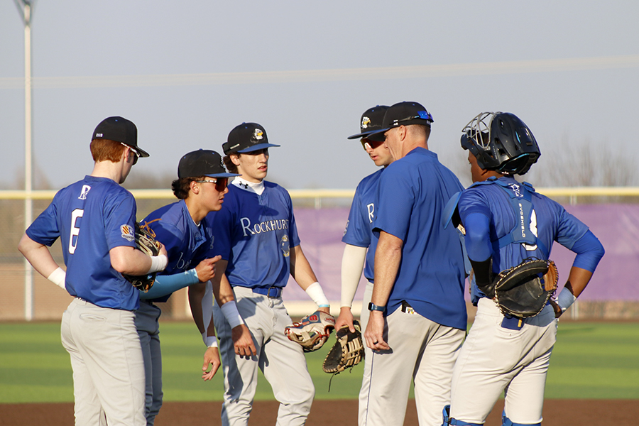 Rockhurst head coach Will Gorden meets with his players on the mound for a pitching change during the road game against Blue Valley Northwest on April 8, 2026. Gorden's team, trailing at the time, would rally late, only to fall in the bottom of the seventh, 7-6. Despite the outcome, Gorden's team sits at .500 this season, a three-win improvement from last year at this point.